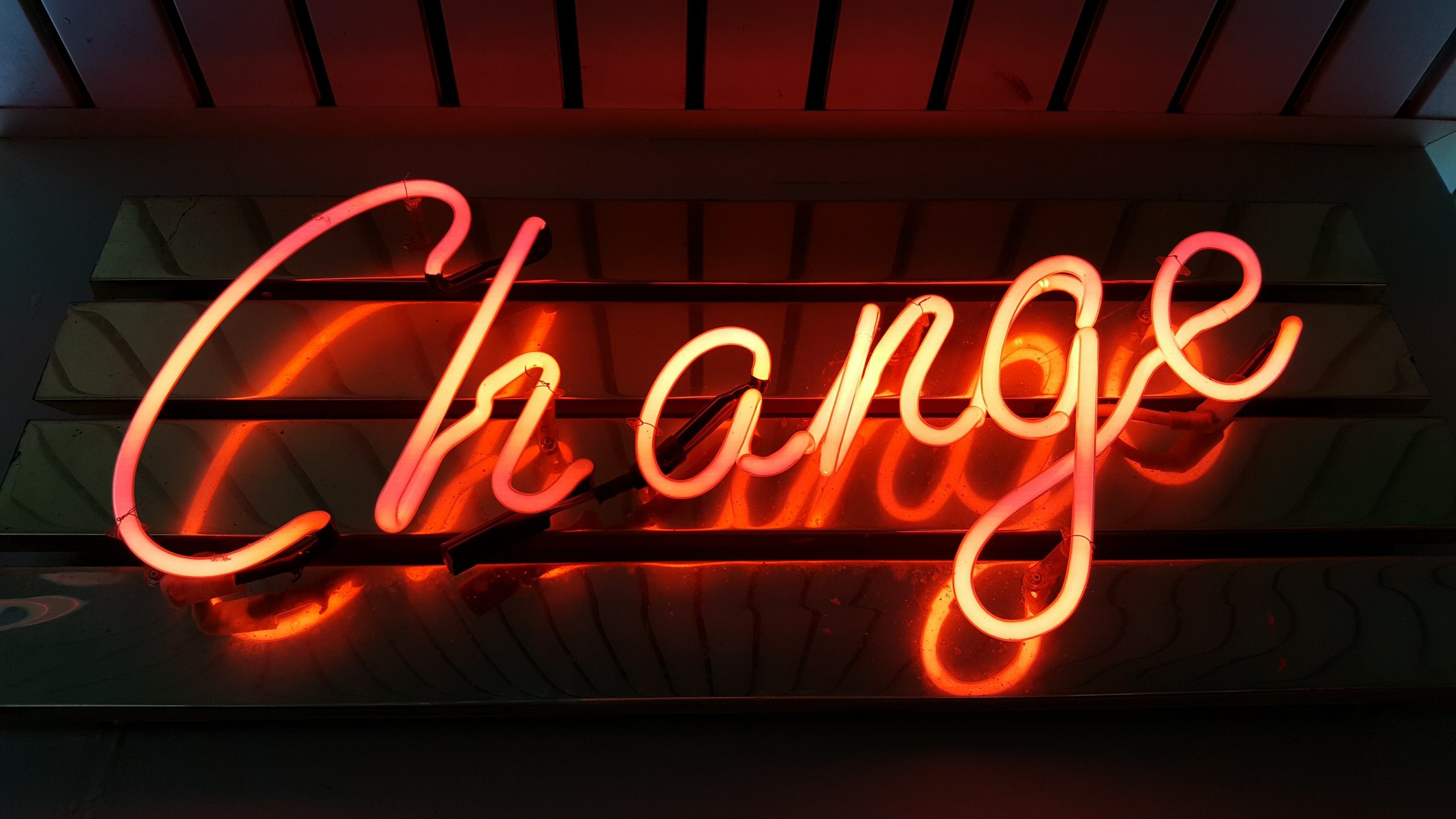 Red and yellow neon sign hanging on dark wall. 